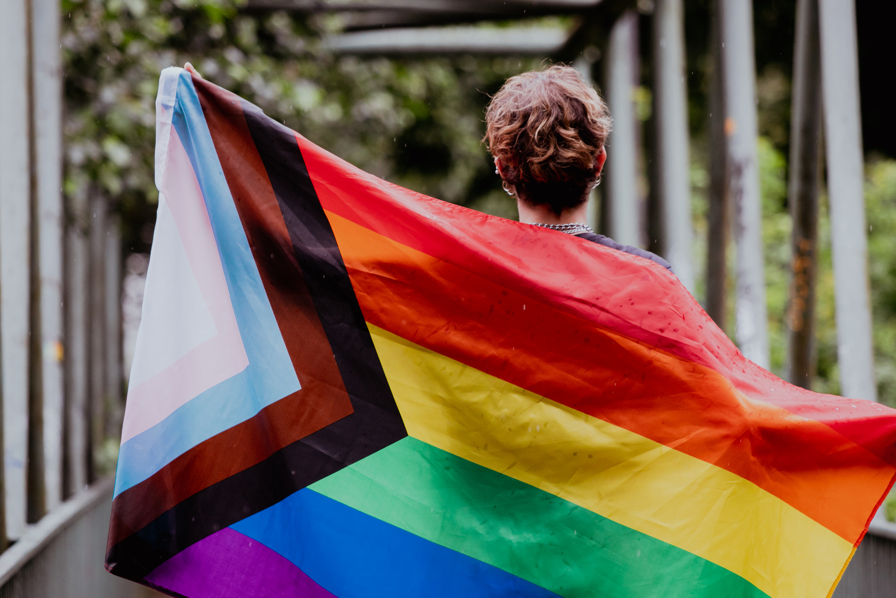 Person Holding a Progress Pride Flag Outdoors 